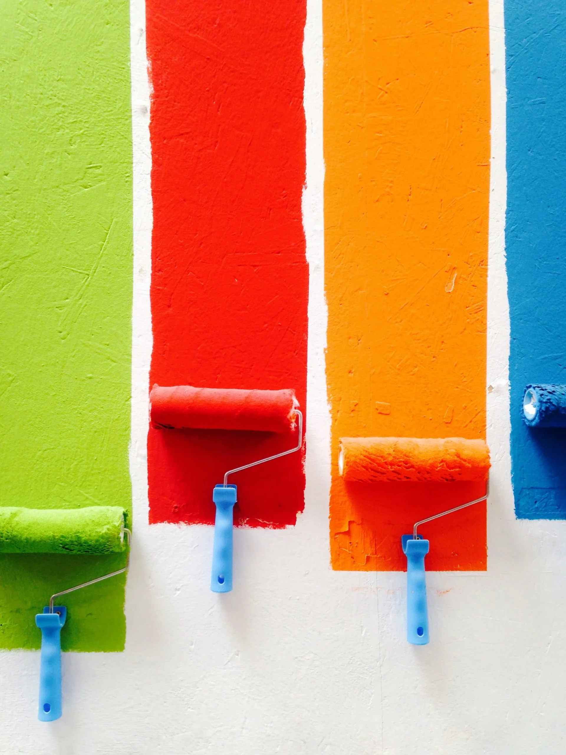 Rouleau à peinture coloré appliquant de la peinture sur un mur, créant un mélange vibrant de teintes pour une rénovation domiciliaire créative.