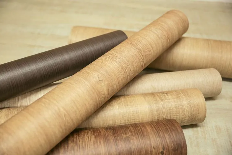 Divers rouleaux de bois disposés sur une table, illustrant la variété des textures et des couleurs du bois.
